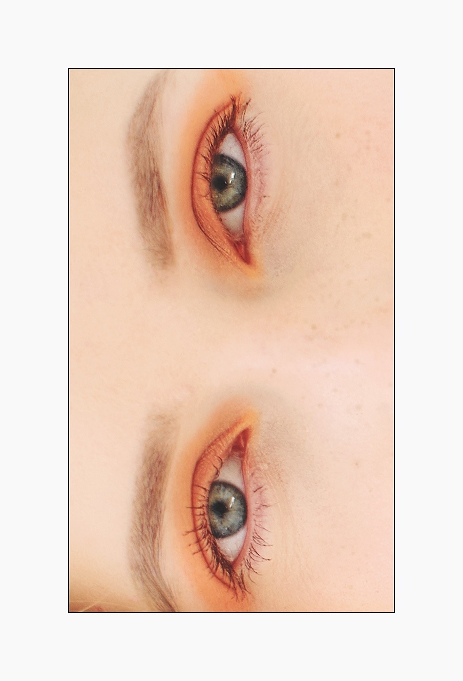 Odwrócone zbliżenie na dwa oczy z pomarańczowym makijażem, podkreślającym rzęsy i brwi. Widoczne drobne piegi na skórze.