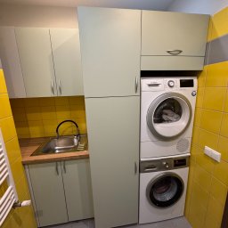 BEE PERFECT - Jasnozielone szafki na wymiar z pralką i suszarką Bosch w żółtej łazience. Kompaktowe rozwiązanie do małych przestrzeni, nowoczesny design, praktyczne zagospodarowanie.