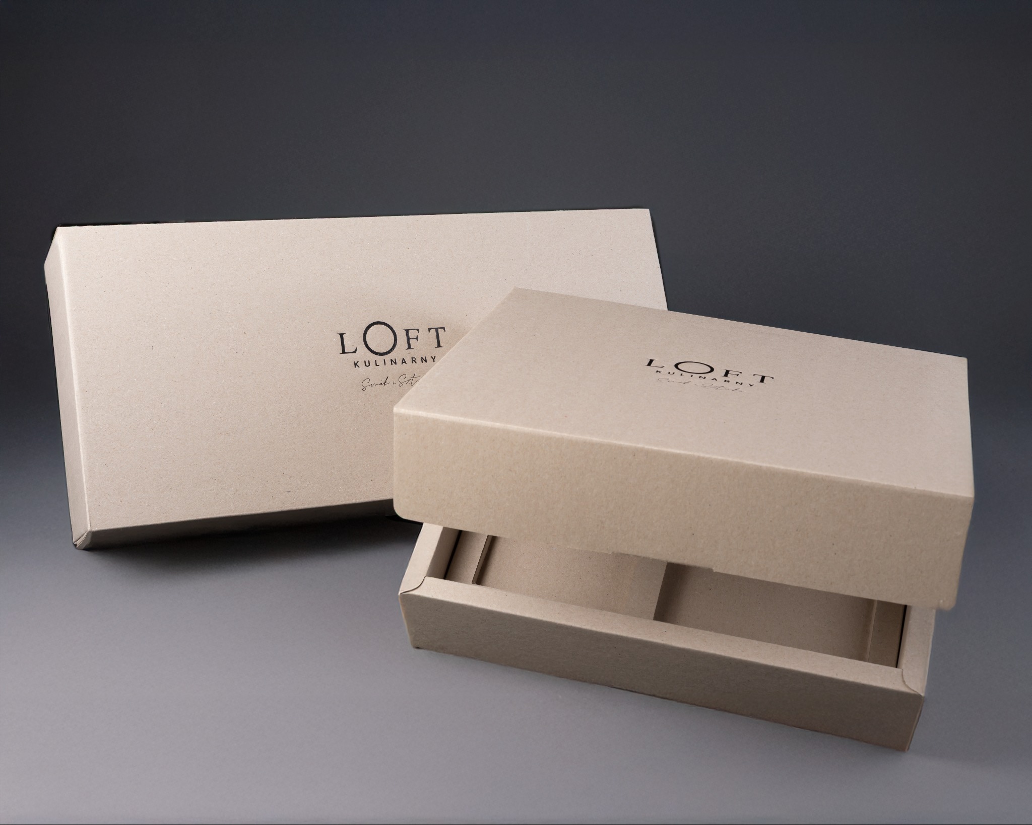 Dwa pudełka z ekologicznego kartonu z logo 'Loft Kulinarny'. Jedno pudełko zamknięte, drugie lekko otwarte, ukazujące wnętrze. Neutralne tło, miękkie światło.