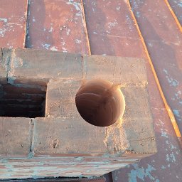 SYSTEMY KOMINOWE Szymon Stokowy - Murowany komin z dwoma otworami na dachu z blachy, oświetlony ciepłym światłem. Widok z góry na konstrukcję komina.