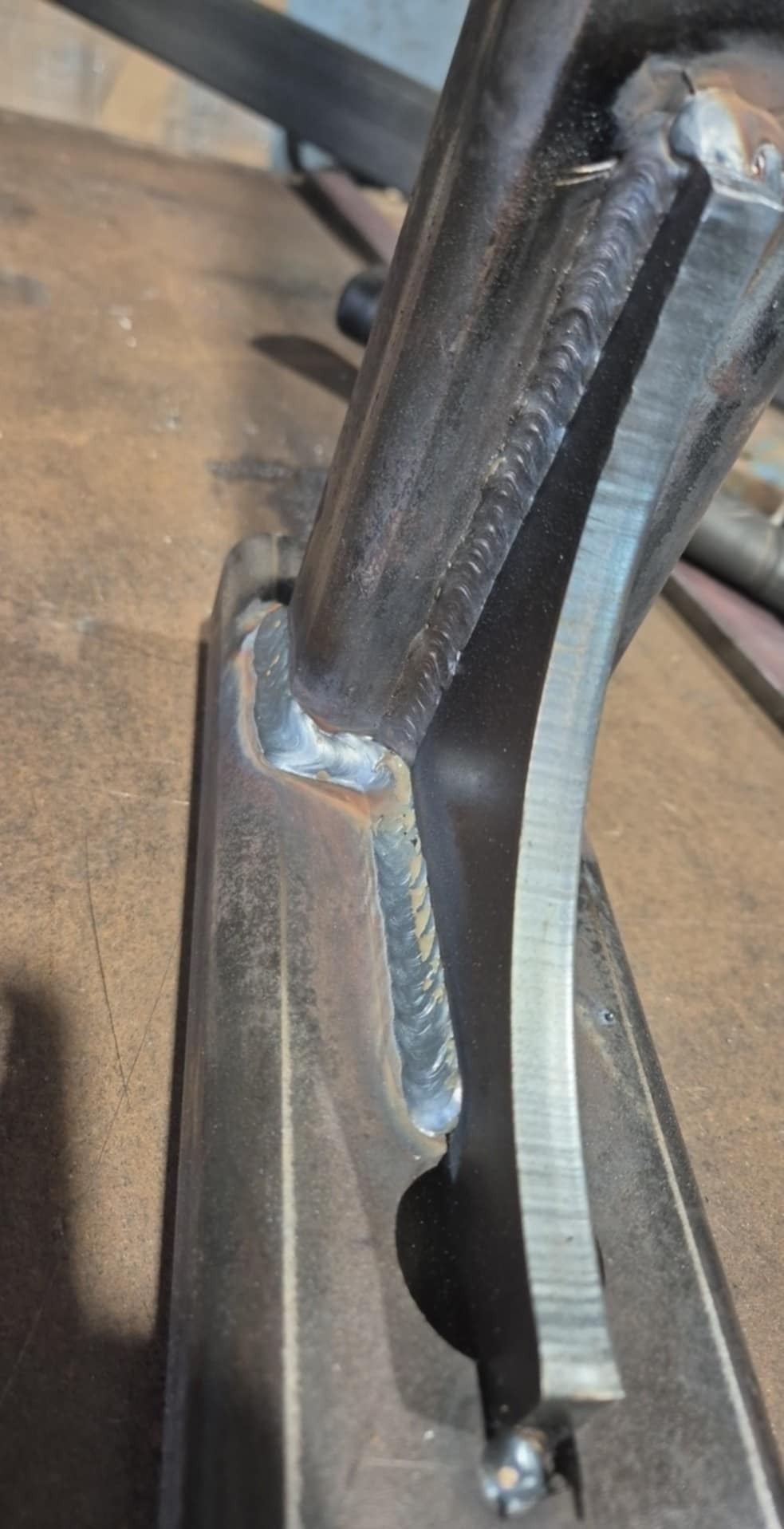 Precyzyjne spawy łączące elementy konstrukcji metalowej. Widoczne ślady obróbki i charakterystyczne złącza po spawaniu, podkreślające rzemiosło.