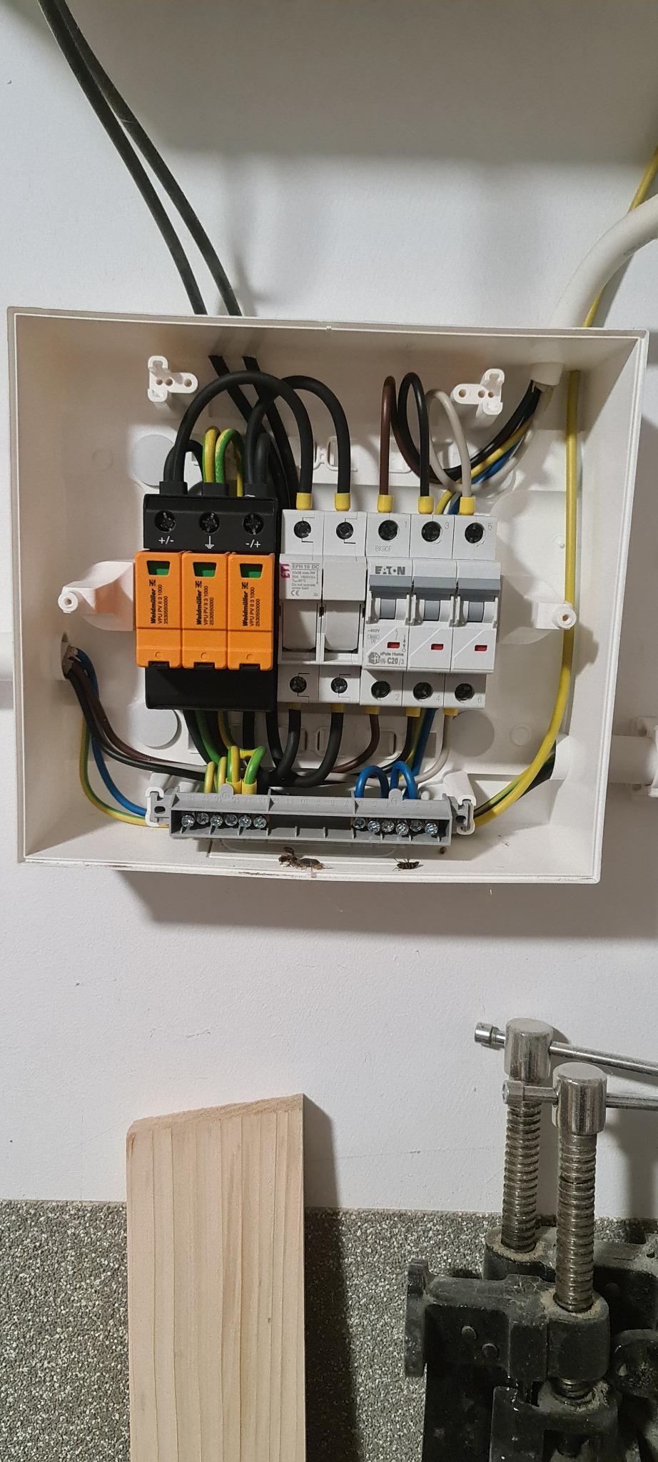 Rozdzielnia elektryczna w białej obudowie z zabezpieczeniami przepięciowymi Weidmüller i wyłącznikami EATON, widoczne kable w różnych kolorach.