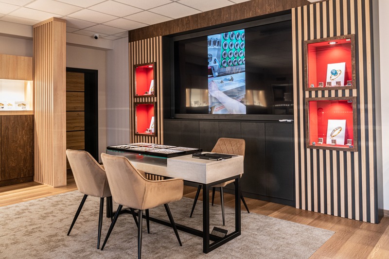 Eleganckie wnętrze butiku jubilerskiego z ekspozycją pierścionków w podświetlanych gablotach i stołem do prezentacji biżuterii, nowoczesny design.