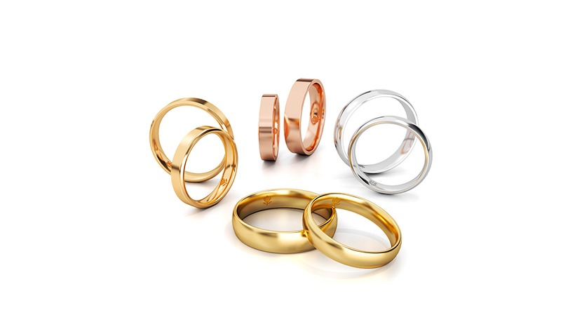 Zestaw lśniących obrączek: złote, różowe i srebrne, ułożone parami na białym tle. Minimalistyczny, elegancki design z delikatnym logo na powierzchni. Idealne na prezent.