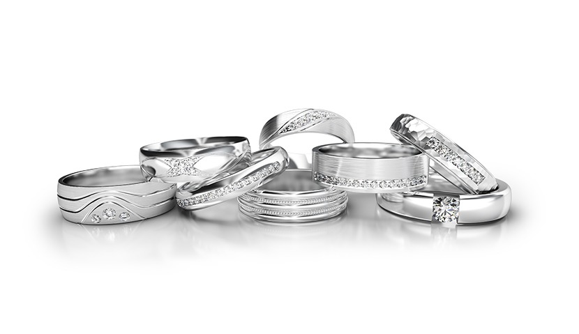 Eleganckie, srebrne obrączki z różnymi wzorami i kamieniami, ułożone na białym tle, idealne na prezent.