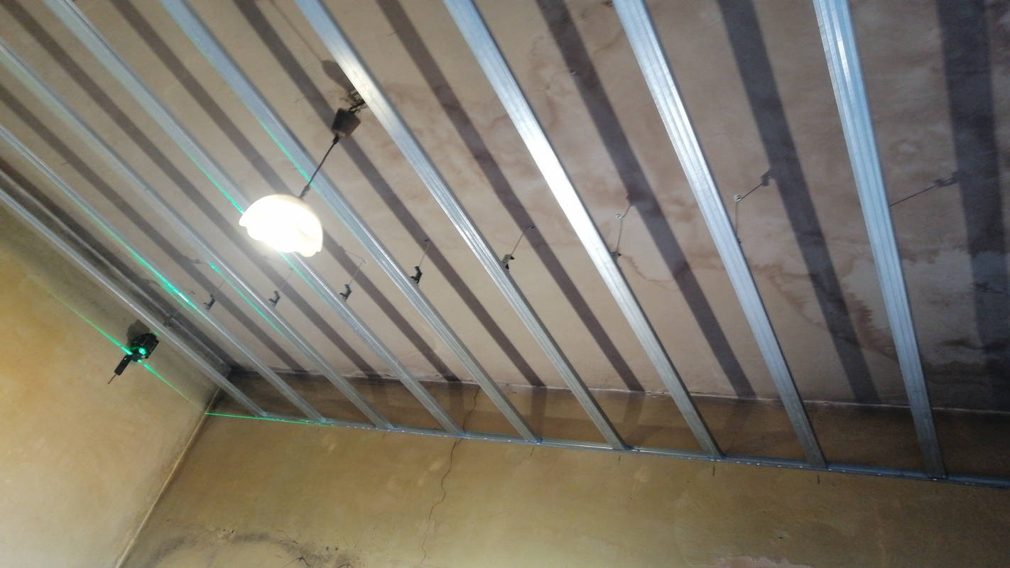 Stelaż sufitu podwieszanego z profili metalowych, wypoziomowany laserowo, widok z dołu w pomieszczeniu w trakcie remontu.
