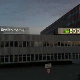 KAPITAN REKLAMA SPÓŁKA Z OGRANICZONĄ ODPOWIEDZIALNOŚCIĄ - Budynek biurowy z logo firm XenicoPharma i inkBOOK na dachu. Billboard Cancer Fighters z prośbą o przekazanie 1,5% podatku. Widok z parkingu.