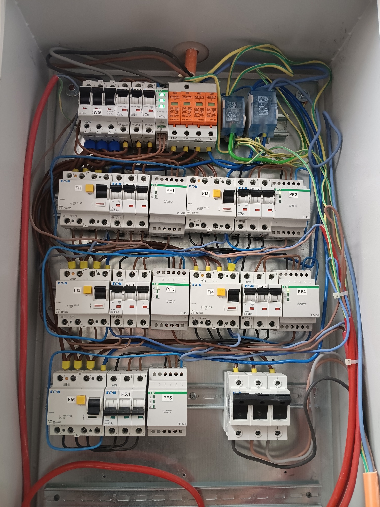 Rozdzielnia elektryczna z bezpiecznikami Eaton, widoczne przewody w różnych kolorach. Instalacja w skrzynce, zabezpieczenia, kable.