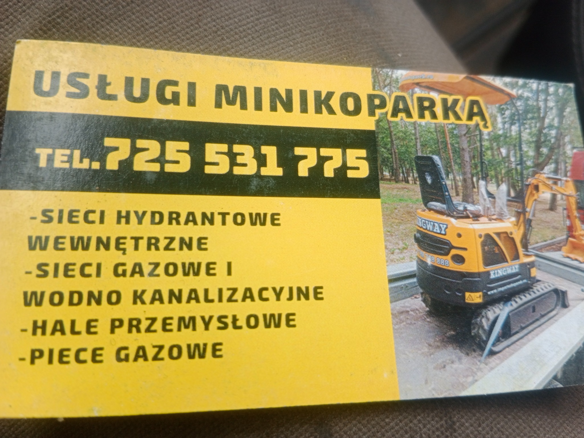 Żółta wizytówka z ofertą usług minikoparką, numerem telefonu i zakresem prac: sieci hydrantowe, gazowe, wodno-kanalizacyjne, hale przemysłowe i piece gazowe.