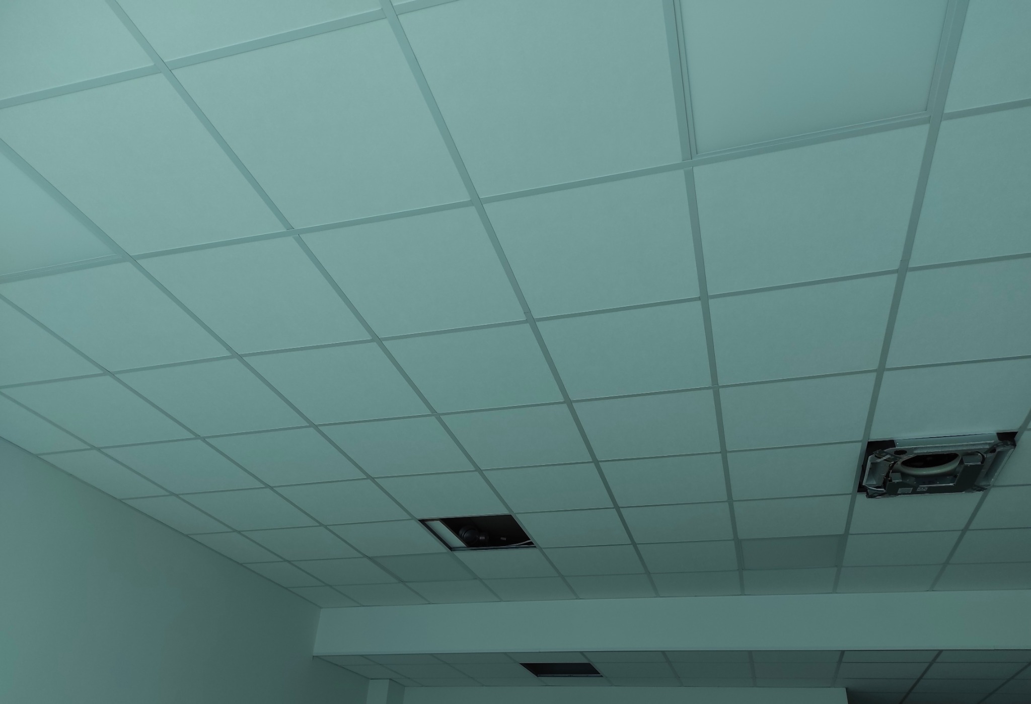 Zamontowany sufit podwieszany z płyt karton gips w biurze w Oławie. Widoczne otwory na oświetlenie i wentylację, równomierne rozmieszczenie płyt.