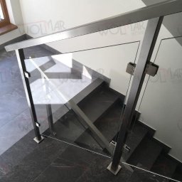 WOLMAR Edyta Wolna - Nowoczesne schody z szarego kamienia z balustradą ze szkła i stali nierdzewnej, widok z góry, minimalistyczny design, ciemna podłoga.