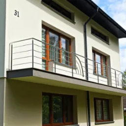 Balkon w nowoczesnym domu z chromowaną balustradą o minimalistycznym designie i elementami giętymi. Widoczne okna z drewnianą stolarką i numer domu '31'.