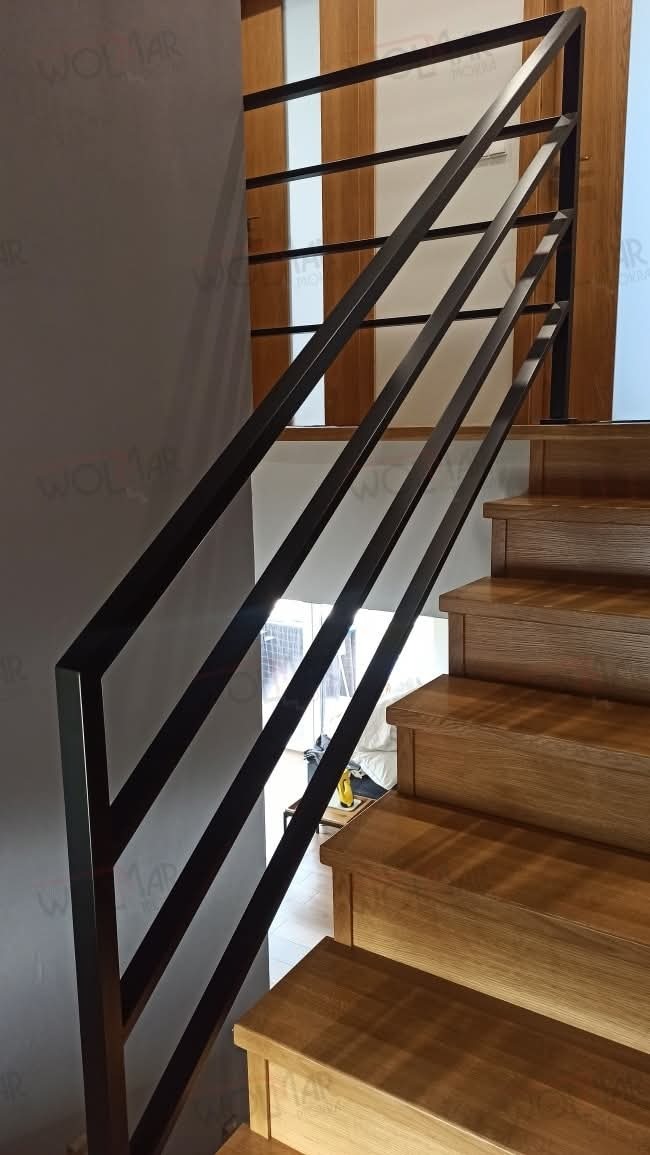 Minimalistyczna balustrada schodowa z czarnych, prostych profili na drewnianych schodach. Nowoczesny design z naturalnym drewnem.