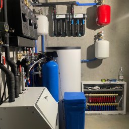TUTTO SPÓŁKA Z OGRANICZONĄ ODPOWIEDZIALNOŚCIĄ - Kompletna kotłownia z filtrami, zbiornikami, rozdzielaczem ogrzewania podłogowego i kotłem. Widok na całą instalację w pomieszczeniu technicznym.