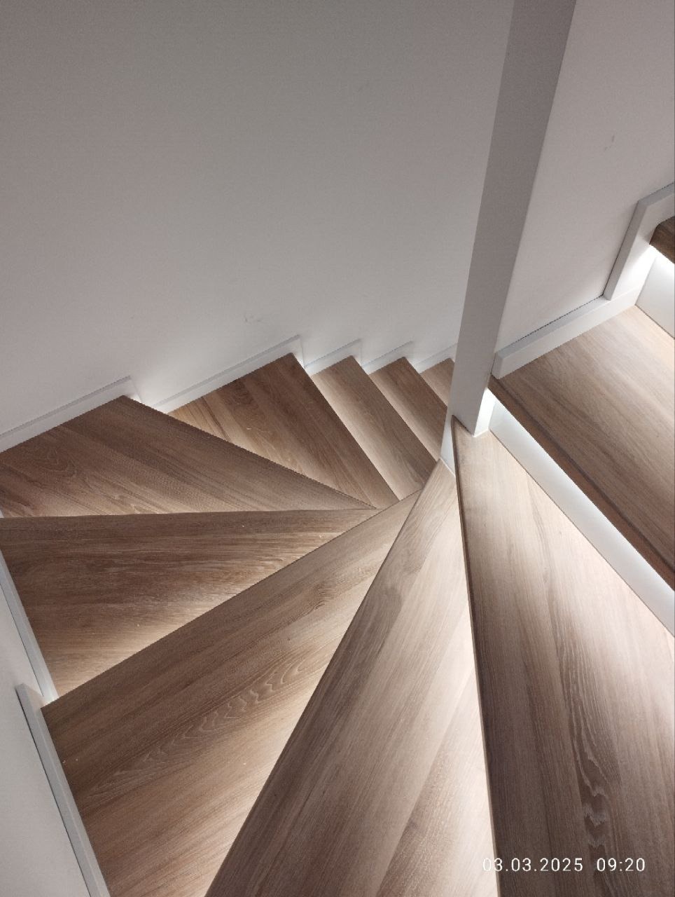 Drewniane schody z oświetleniem LED pod stopniami, widok z góry, biała ściana i balustrada, nowoczesny design, jasne drewno, ukończony projekt.