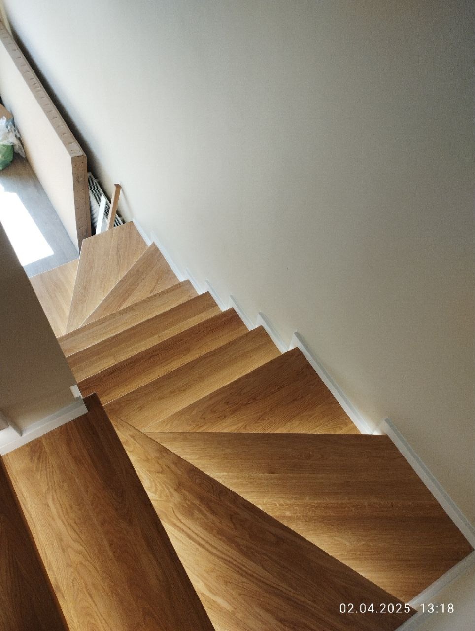 Nowoczesne schody z drewna dębowego, widok z góry, ukazujący wzór ułożenia klepek. Jasne wnętrze, minimalistyczny styl.