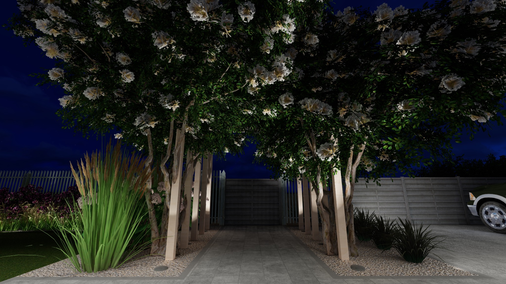 Iluminacja ogrodu nocą: aleja drzew z białymi kwiatami, oświetlona lampami wzdłuż ścieżki z kostki, z widocznym fragmentem ogrodzenia i samochodu w tle.