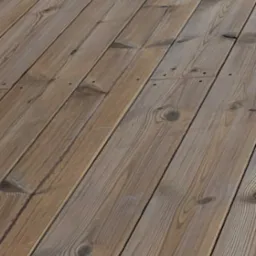 Ukończony taras z desek z widocznymi słojami drewna i gwoździami, ułożony pod kątem, z fragmentem brązowej ściany w tle. Drewno ma naturalny, ciepły odcień.