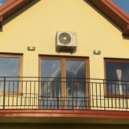 Energy Power Group - Żółty dom z balkonem i zamontowaną klimatyzacją Gree Pular 3,2 KW. Widoczne okna z odbiciem nieba. Na górze napis 'Nasze ostatnie montaże'.