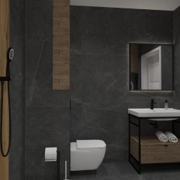 Sedno Przestrzeni Anna Sułot - Nowoczesna łazienka z drewnianymi i grafitowymi płytkami, czarną armaturą i minimalistyczną umywalką z szafką. W lustrze odbija się fragment wnętrza.