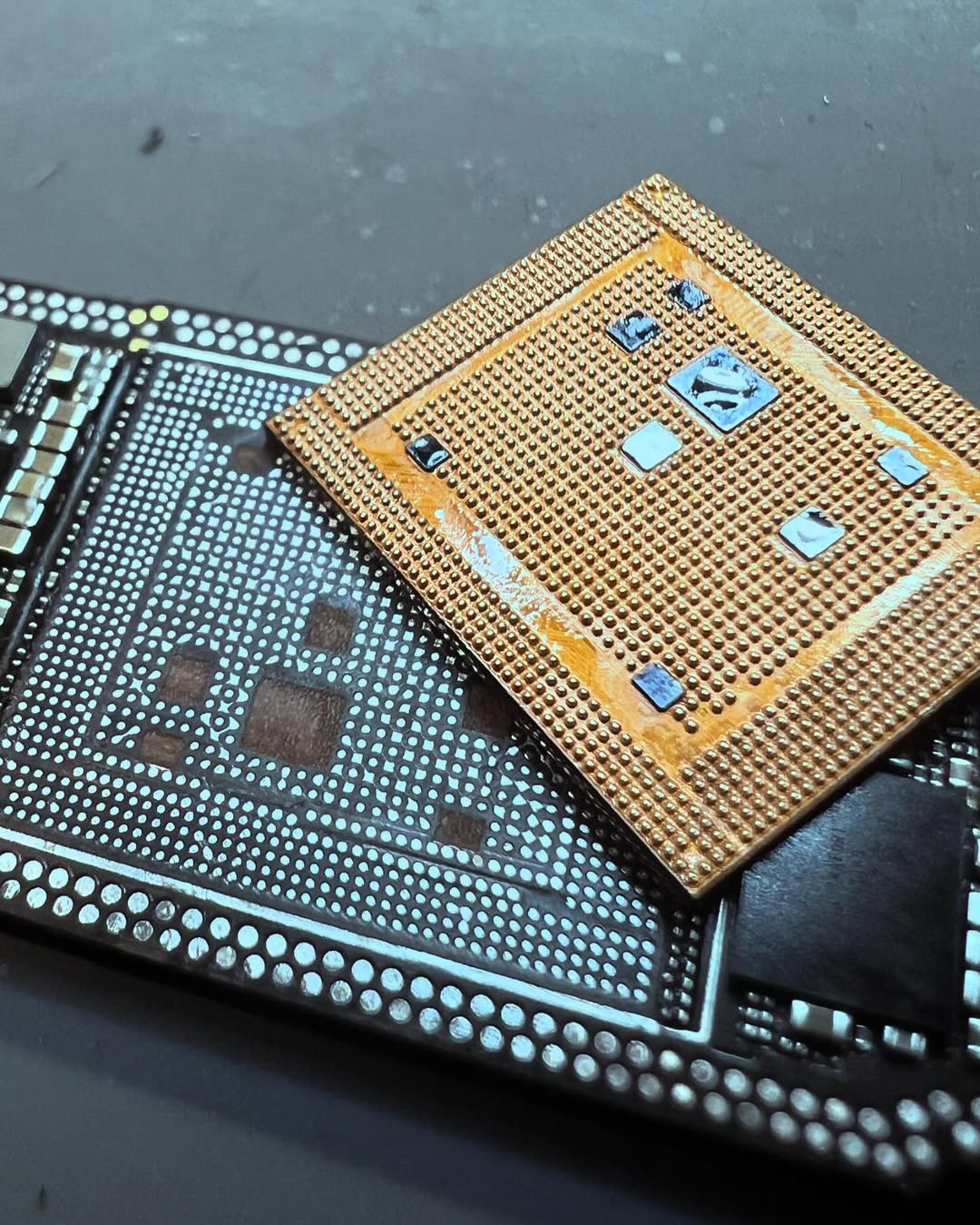 Zbliżenie na płytę główną telefonu z układem BGA, widoczne kule lutownicze i ślady topnika. Precyzyjna naprawa elektroniki.