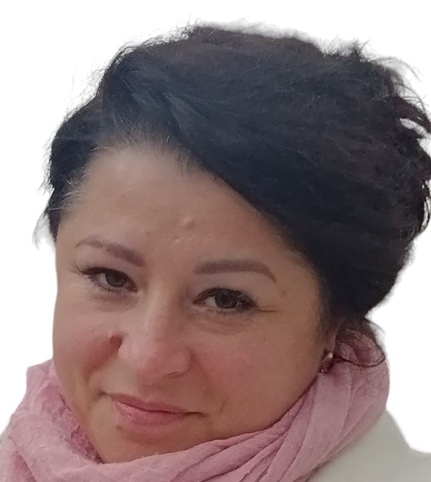 Portret kobiety z ciemnymi włosami i różowym szalem, uśmiechająca się, z widocznymi zmarszczkami mimicznymi wokół oczu, na jasnym tle.