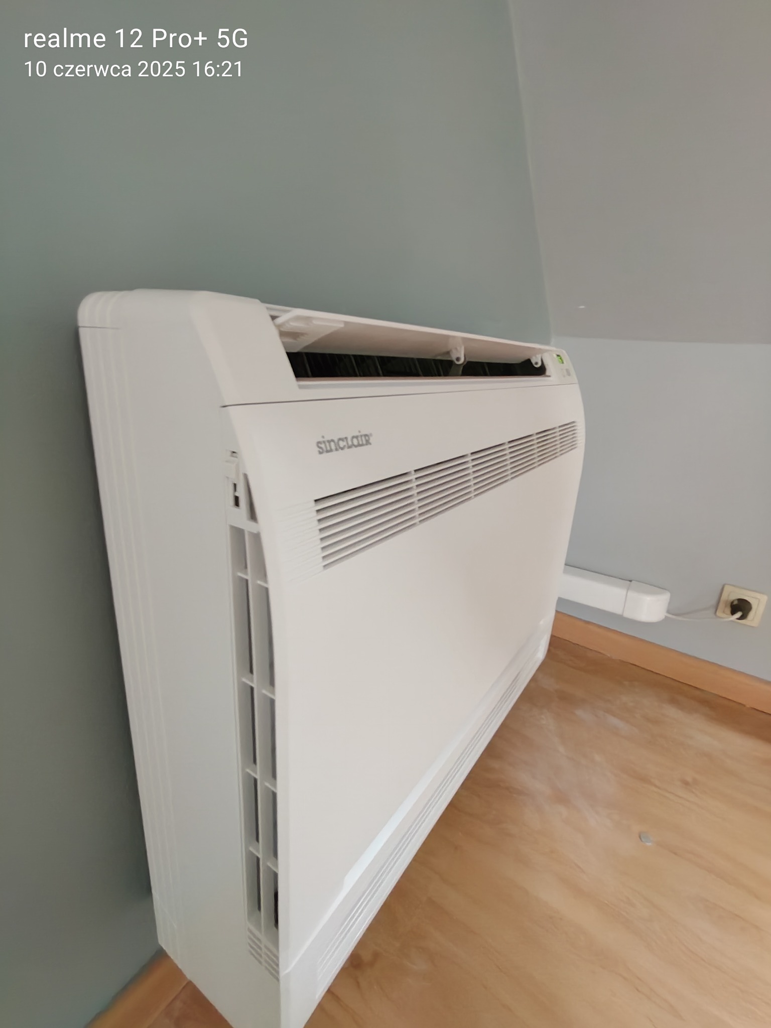 Klimatyzator Sinclair przypodłogowy w jasnym wnętrzu, widoczny przewód zasilający. Montaż klimatyzacji w domu, Gliwice.