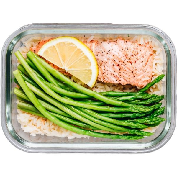Lunchbox z grillowanym łososiem, ryżem i szparagami, udekorowany plasterkiem cytryny. Zdrowy posiłek w szklanym pojemniku.