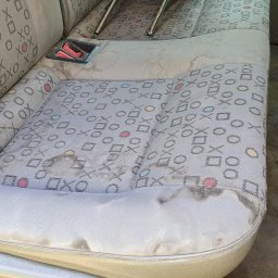 Flame Mariusz Wnuk - Silnie zabrudzone, szare siedzenie samochodowe z wzorem kółek, krzyżyków i kwadratów przed czyszczeniem. Widoczne plamy i zabrudzenia na tapicerce.