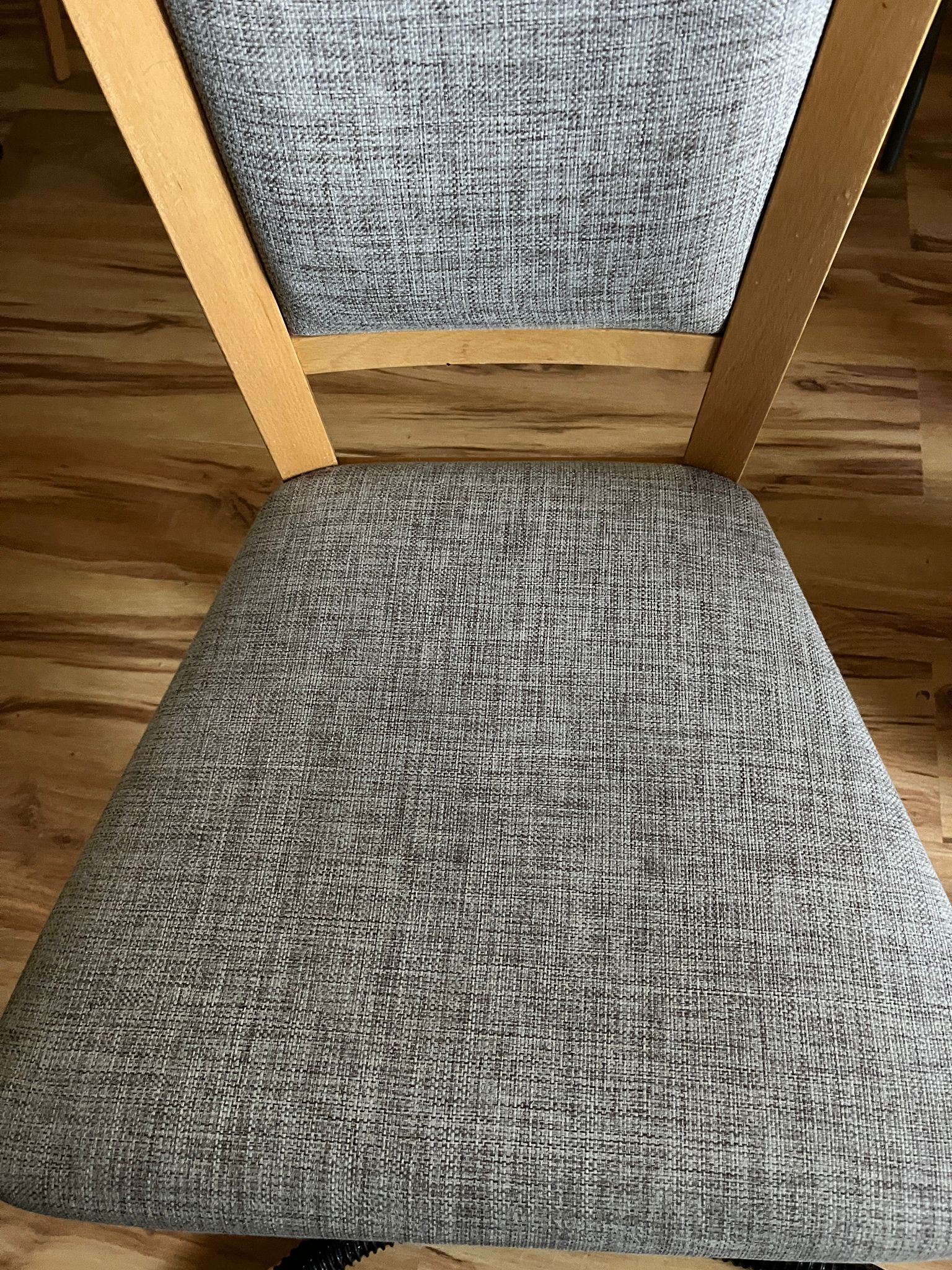 Krzesło z jasną, drewnianą ramą i szarą tapicerką o wyraźnej fakturze, po czyszczeniu, na tle drewnianej podłogi.