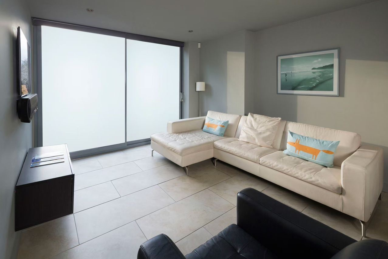 Nowoczesny salon z przesuwnymi drzwiami szklanymi z mlecznym szkłem, zapewniającymi prywatność i doświetlenie, sofa z poduszkami z motywem lisa.