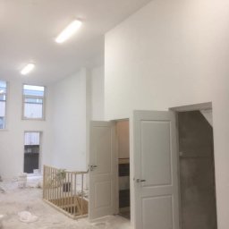 Malta - Wnętrze po remoncie: białe ściany, dwoje otwartych drzwi, drewniana balustrada schodów. Widoczne ślady po pracach wykończeniowych.