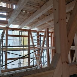 Malta - Wnętrze domu szkieletowego w trakcie budowy. Widoczne drewniane elementy konstrukcyjne, rusztowania i folia ochronna na oknach. Konstrukcja dachu z desek.