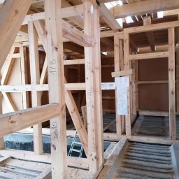 Malta - Konstrukcja domu szkieletowego w trakcie budowy. Widoczne drewniane ramy z oznaczeniami, schodki i plany architektoniczne na ścianie.