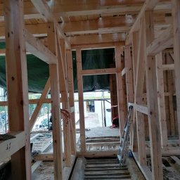 Malta - Wnętrze domu w trakcie budowy, widoczna drewniana konstrukcja szkieletowa, schody betonowe i drabina oparta o ścianę. Surowy stan, widoczne elementy instalacji.