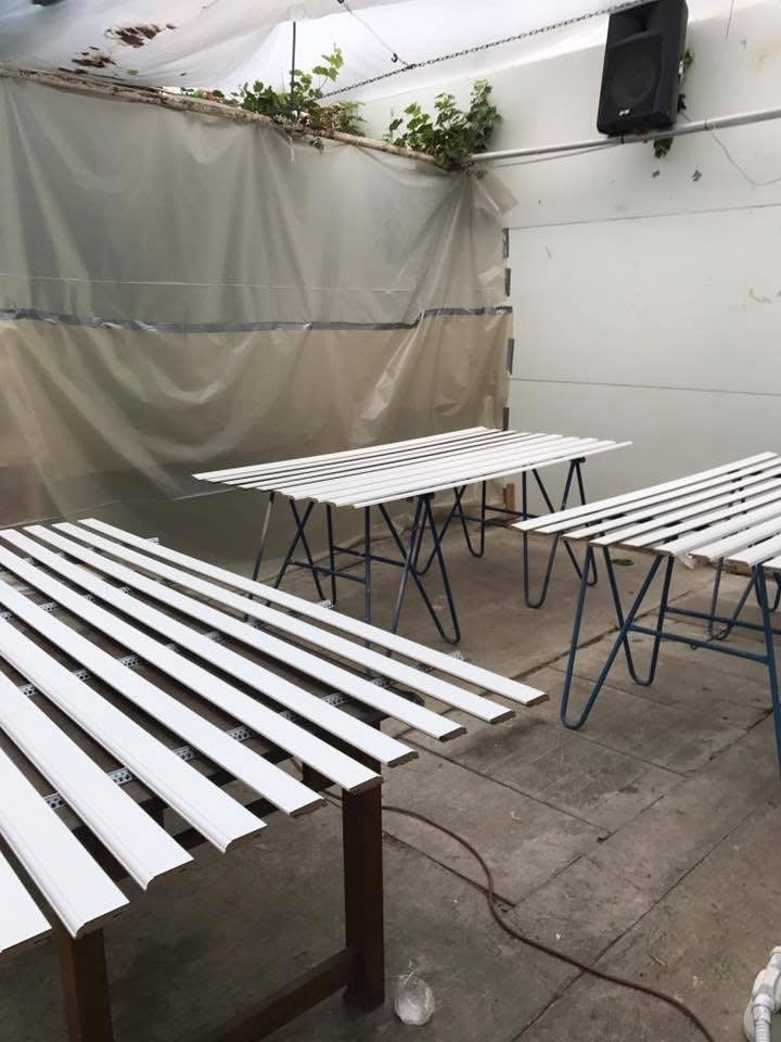 Malowanie listew przypodłogowych na biało w Gorzowie Wielkopolskim. Listwy leżą na stołach w pomieszczeniu przygotowanym do malowania, z folią i roślinami.