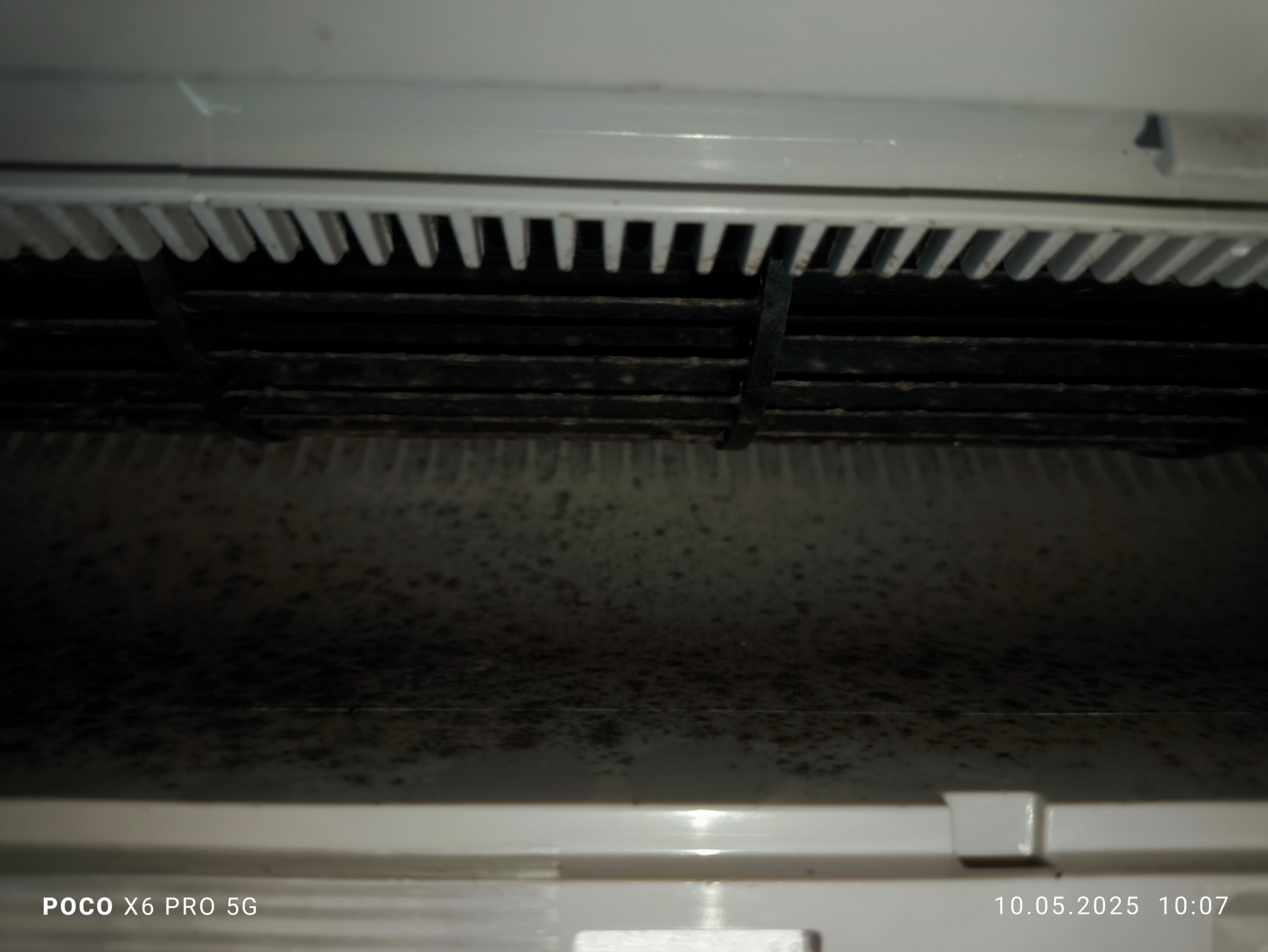 Zanieczyszczone wnętrze klimatyzatora z widocznymi zabrudzeniami i zaciekami. Filtr powietrza zakurzony. Zdjęcie z bliska, ukazujące szczegóły.