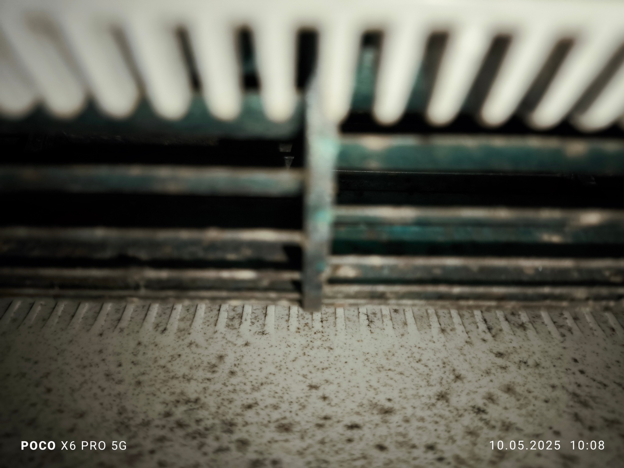 Brudne, zaniedbane wnętrze klimatyzatora z widocznymi lamelami i zabrudzeniami. Perspektywa z dołu, ciemne oświetlenie, szczegółowe ujęcie stanu przed czyszczeniem.