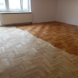 Lewon - Parkiet w jodełkę po renowacji: połowa powierzchni wycyklinowana i polakierowana, druga połowa surowa. Widoczny fragment osoby. Okno z grzejnikiem w tle.