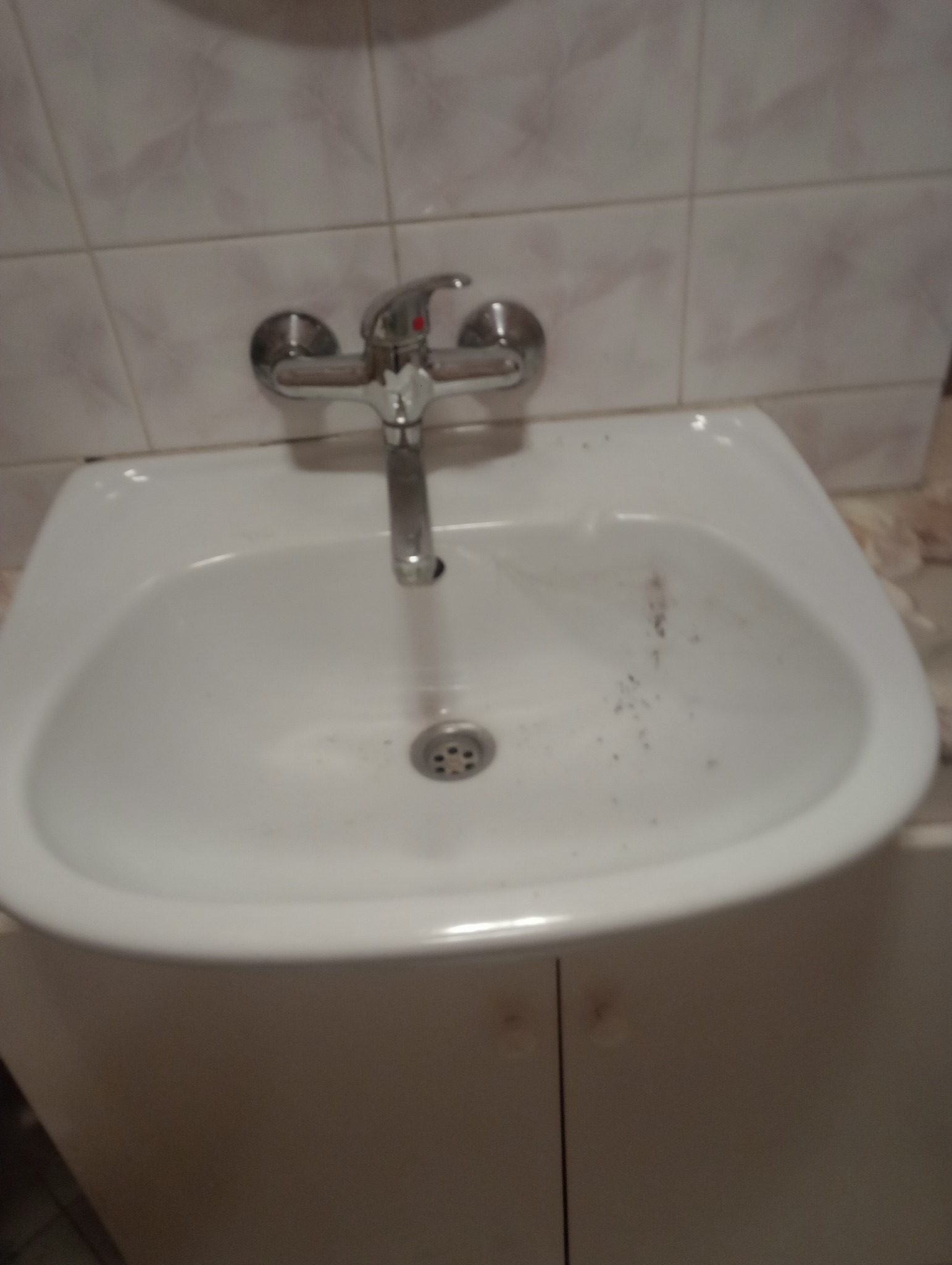 Zanieczyszczona umywalka z widocznymi zabrudzeniami i osadem, wymagająca czyszczenia w Łubowie. Bateria chromowana, biała ceramika i płytki w tle.