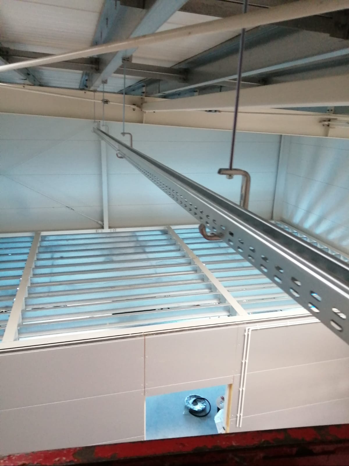 Metalowa konstrukcja podwieszona do sufitu, prawdopodobnie koryto kablowe lub element instalacji. Widoczne mocowania i perforowane profile.