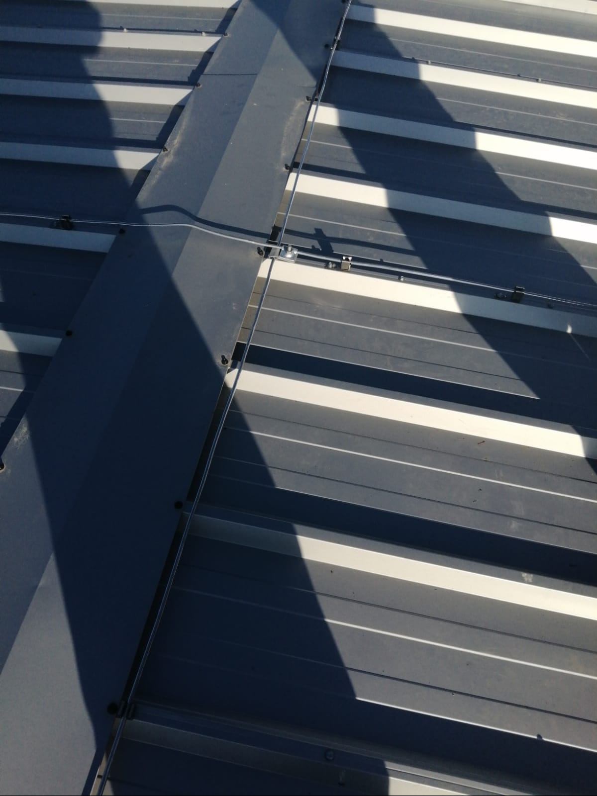 Metalowy dach z zamontowaną instalacją odgromową, zabezpieczoną przed wpływem warunków atmosferycznych, widoczne mocowania i przewody.