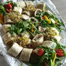 Młyn catering - Tortilla wraps z rukolą, kiełkami i pomidorami na srebrnej tacy z koronkową serwetą, gotowe do serwowania na przyjęciu.