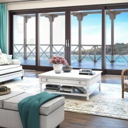 OLSZAR TOMASZ SYLMAR OKNO - Salon z dużymi, przesuwnymi drzwiami balkonowymi z widokiem na morze. Turkusowe zasłony i jasne meble tworzą przytulną atmosferę.