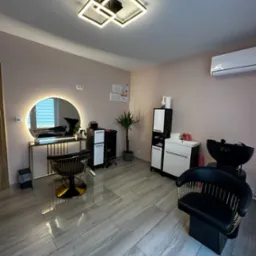 Nowoczesne wnętrze salonu kosmetycznego: lustro z podświetleniem, fotel fryzjerski i stanowisko do mycia włosów. Minimalistyczny design, subtelne oświetlenie.