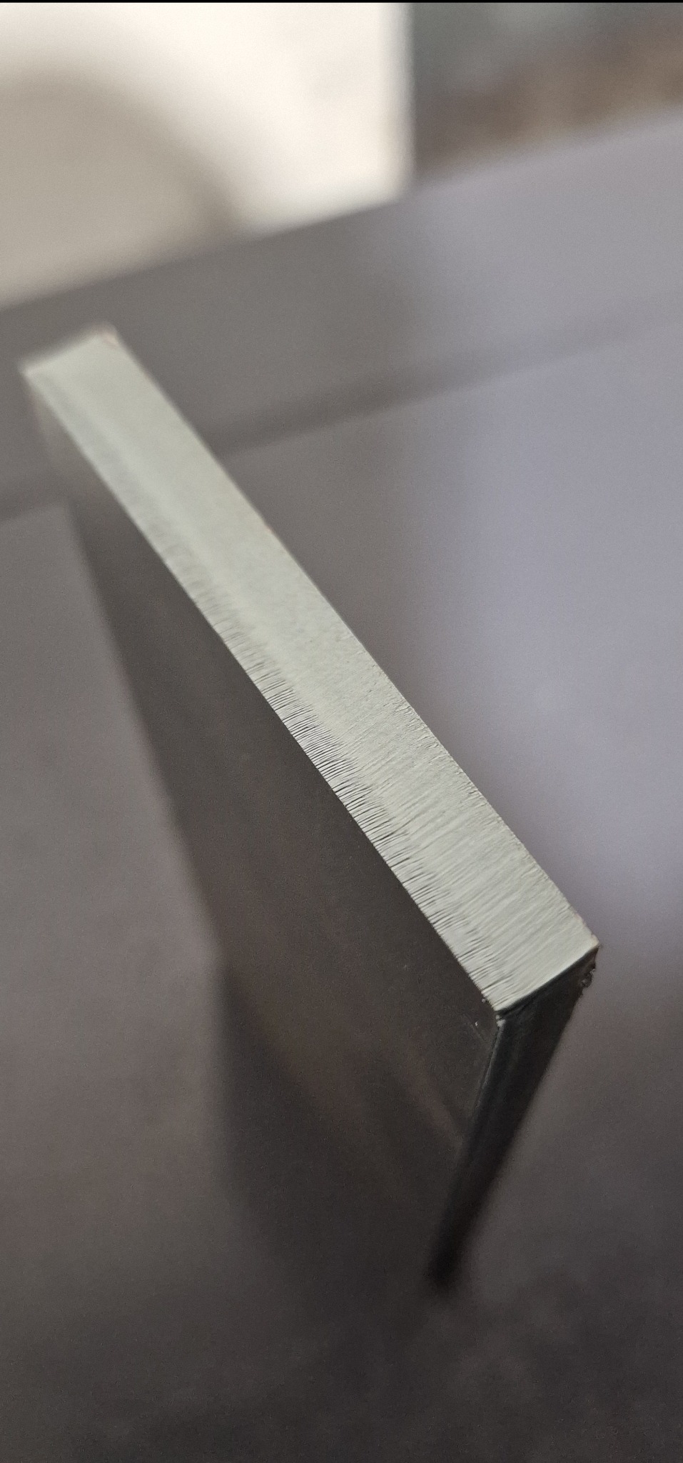 Szlifowany, metalowy profil o prostokątnym przekroju, ukazujący precyzję obróbki i gładką powierzchnię. Widoczne drobne ślady po frezowaniu.