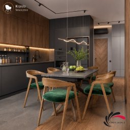 Edite Meble - Nowoczesna kuchnia z ciemnoszarymi szafkami i drewnianymi panelami. Jadalnia z sześcioma drewnianymi krzesłami z zielonym welurowym obiciem wokół ciemnego stołu. Falista lampa wisząca nad blatem.