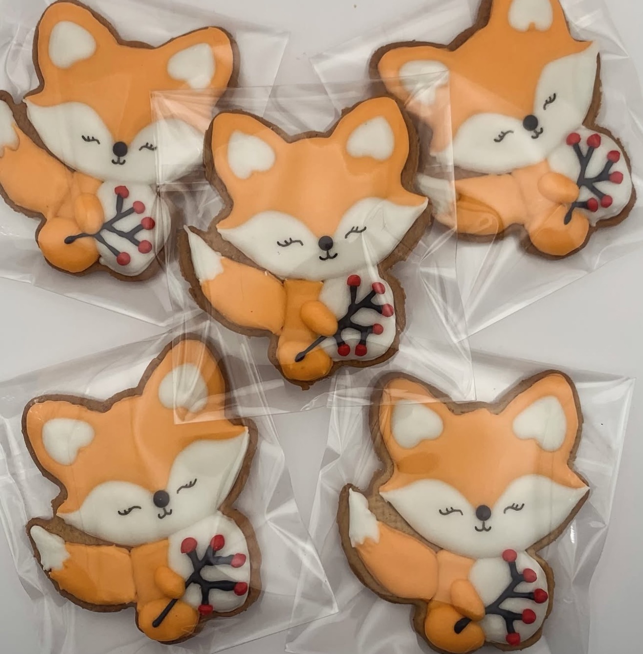 Pięć uroczych, ręcznie robionych pierniczków w kształcie lisów z lukrem, zapakowanych w folię, idealnych na prezent.