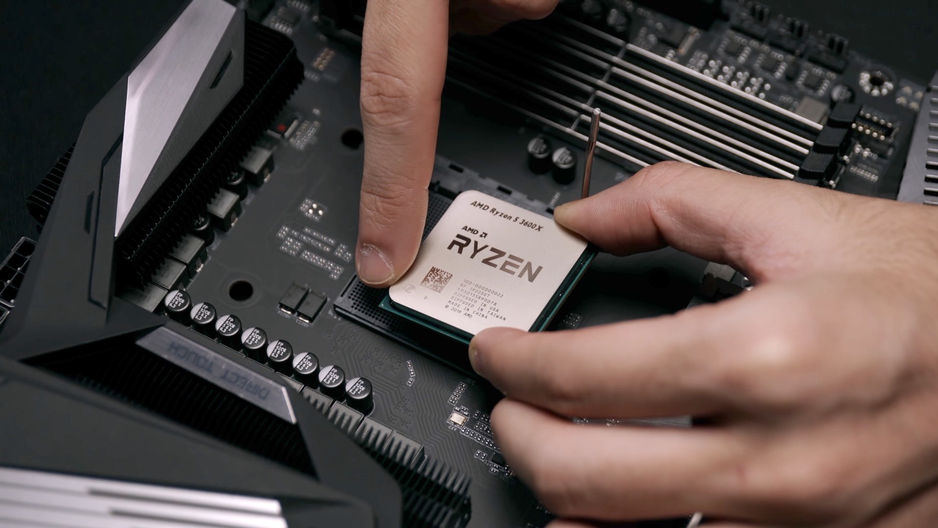 Montaż procesora AMD Ryzen 5 3600X na płycie głównej w Białymstoku. Widoczne ręce instalujące CPU. Detaliczne zbliżenie na gniazdo procesora i chip.