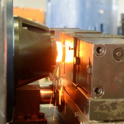 ZOK-TECH - Metalowy element obrabiany w tokarce, z widocznymi iskrami podczas cięcia. Ujęcie z bliska, ukazujące detale procesu obróbki.